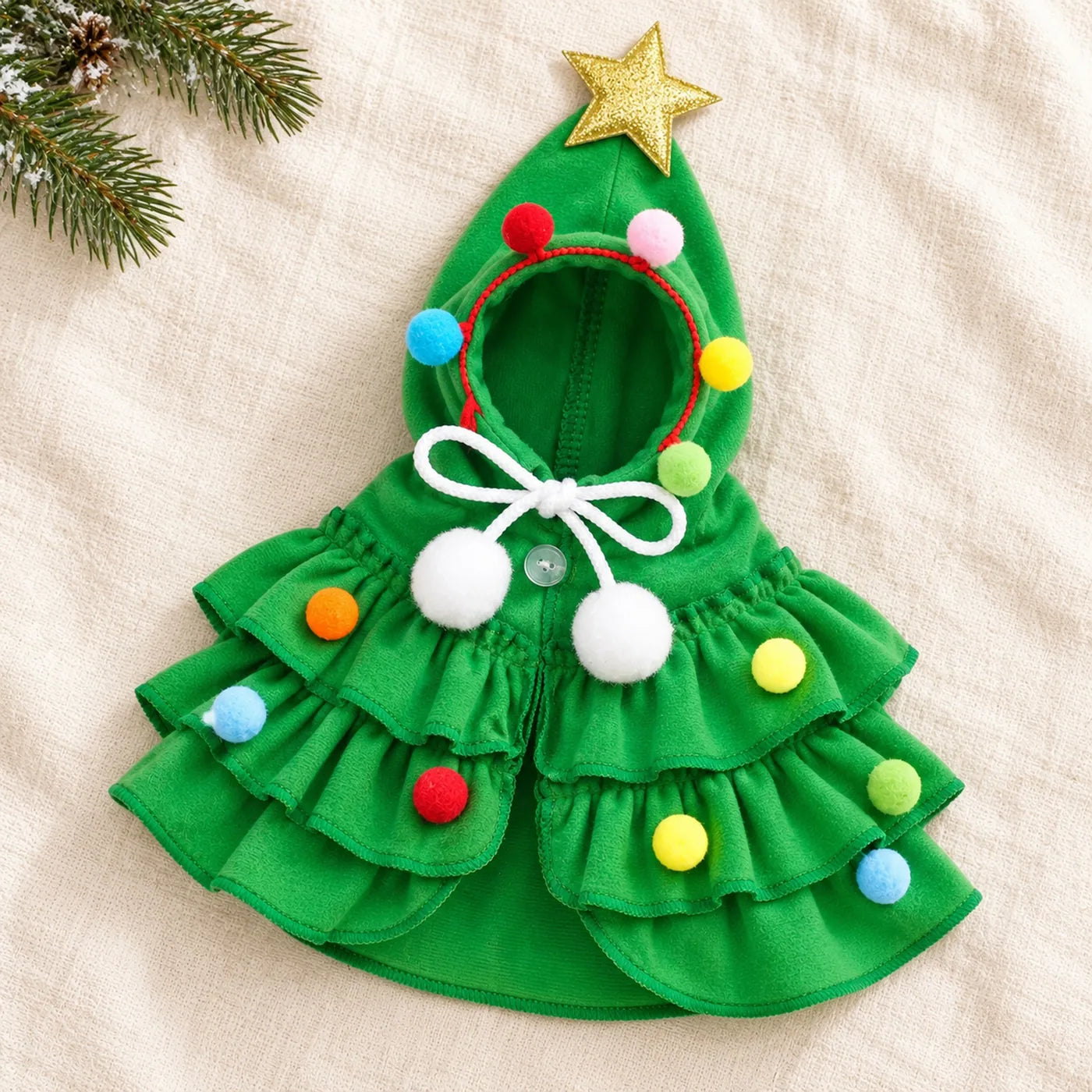 The green Christmas tree costume laid flat: star-topped hood, pom-pom trim, white bow and tiered ruffles
